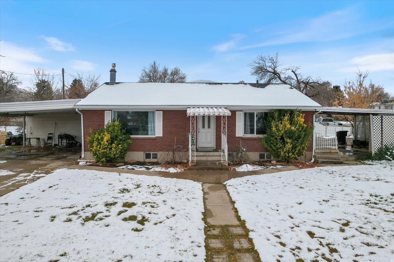 Bungalow with brick siding and an attached carport